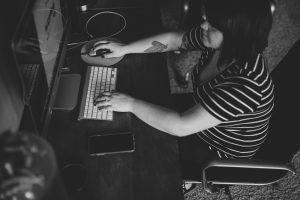 Black and white photo of Misty creating social media content on her computer. Photo by Val Demo.